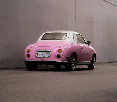A vintage pink car parked against a city wall, showcasing retro style. 4k aesthetic wallpaper