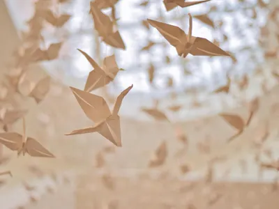 Dreamy paper origami cranes hanging beautifully in a soft indoor light. 4k aesthetic wallpaper