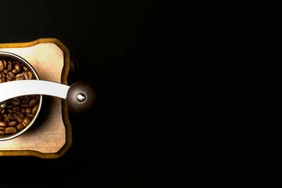 Top-view of a wooden coffee grinder filled with roasted beans on a black backgro 4k aesthetic wallpaper