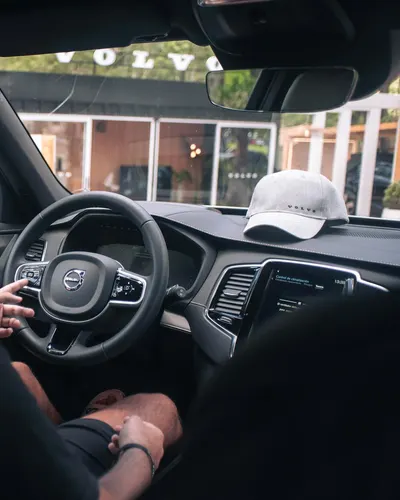 A man driving a modern car with a focus on the interior and steering. 4k cars wallpaper