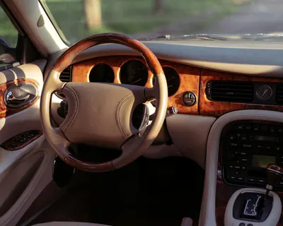 Elegant car interior featuring wooden accents and a stylish steering wheel. 4k cars wallpaper