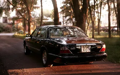 Elegant Jaguar sedan parked in scenic outdoor setting, reflecting warm evening l 4k cars wallpaper