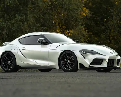 Sleek silver sports car parked on an asphalt road surrounded by lush greenery. 4k cars wallpaper