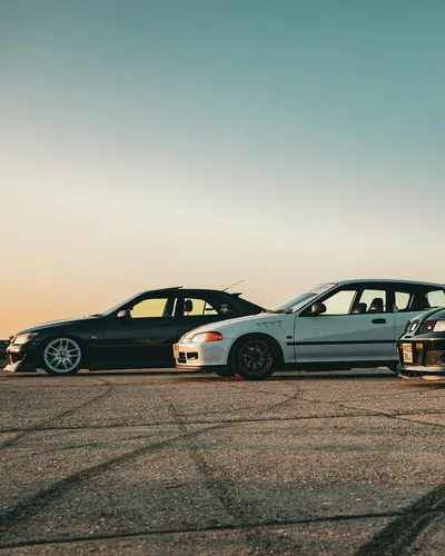 Three tuned sports cars parked on asphalt at sunset, showcasing vehicle customiz 4k cars wallpaper