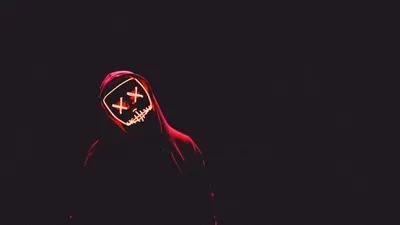 A mysterious figure in a glowing neon mask and dark hoodie set against a black b 4k dark wallpaper