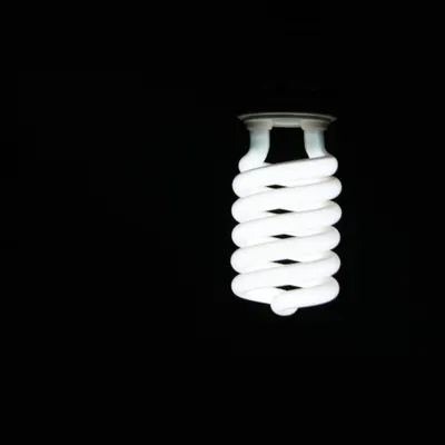 Bright spiral LED lightbulb against black background, artistic minimalism. 4k dark wallpaper