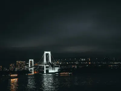 Stunning view of Tokyo's Rainbow Bridge at night, reflecting city lights over th 4k dark wallpaper
