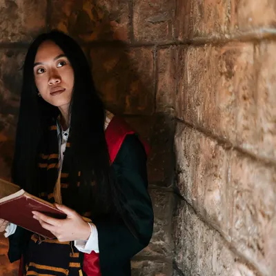 A woman in a wizard costume holding a spellbook, evoking a magical atmosphere. 4k fantasy wallpaper