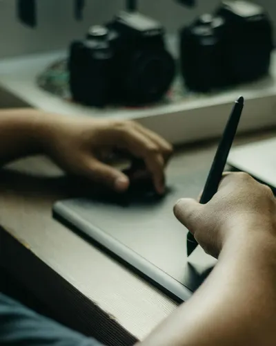 Person using a graphic tablet alongside laptop for digital design work indoors. 4k gaming wallpaper