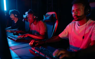 Three gamers immersed in a competitive setting with neon lighting, using keyboar 4k gaming wallpaper