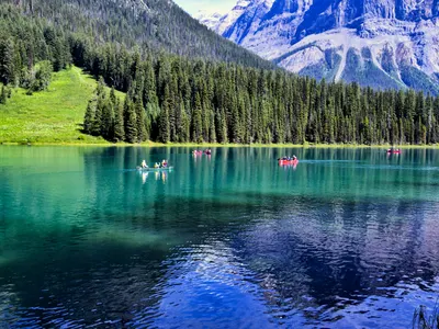 Canoes glide on the serene waters of Emerald Lake in British Columbia, surrounde 4k lake wallpaper
