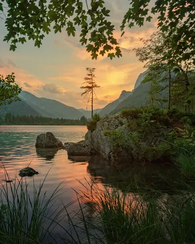 Peaceful sunset over a lake surrounded by mountains and lush greenery, capturing 4k lake wallpaper