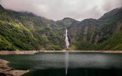 Serene landscape of a waterfall cascading into a lake in Oô, Occitanie, France. 4k lake wallpaper
