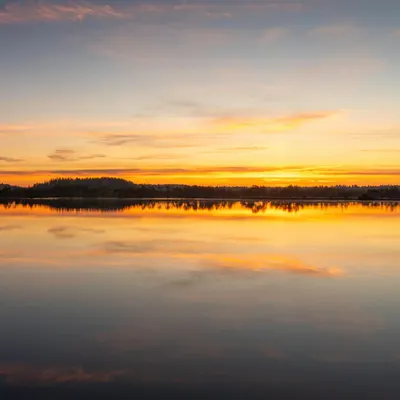 Stunning sunset reflection over a tranquil lake with vibrant skies. 4k lake wallpaper