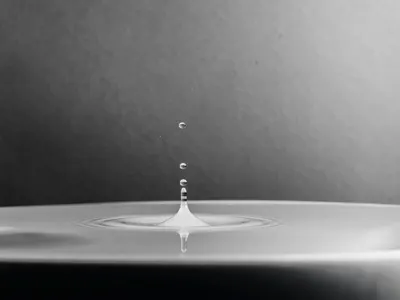 A high-definition macro shot capturing a water drop splash in black and white. 4k macro wallpaper