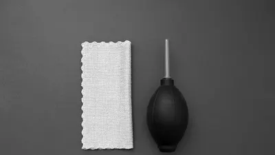 Overhead view of a camera cleaning blower and microfiber cloth on a gray backgro 4k minimal wallpaper