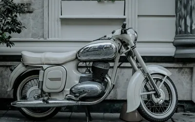 A classic Jawa 353 motorcycle parked by a city building showcases vintage chrome 4k motorcycle wallpaper