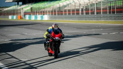 A male motorcyclist in full gear is racing on a track during the day, showcasing 4k motorcycle wallpaper