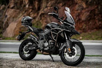 A modern adventure motorcycle parked on a scenic road with rocky terrain in the  4k motorcycle wallpaper