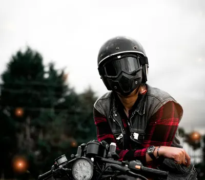 An adult motorcyclist wearing a helmet and vest on a bike, outdoors. 4k motorcycle wallpaper