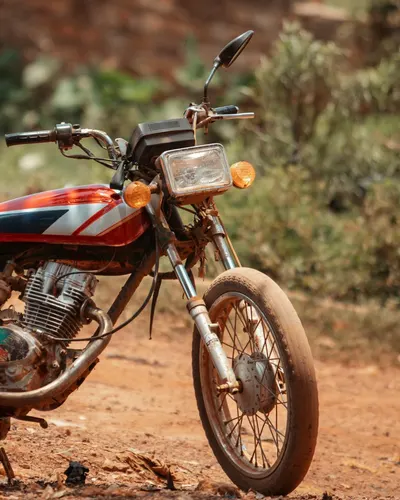 Classic motorbike parked on a rural dirt path, evoking nostalgia. 4k motorcycle wallpaper