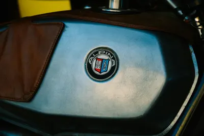Detailed close-up of a classic Alpina motorcycle logo on a leather-accented fuel 4k motorcycle wallpaper
