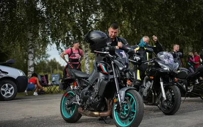 Group of motorcyclists adjusting gear beside bikes at a meetup on a sunny day. 4k motorcycle wallpaper