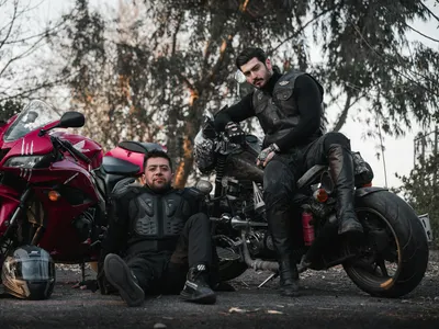 Two bikers in gear pose confidently with motorcycles on an outdoor setting. 4k motorcycle wallpaper