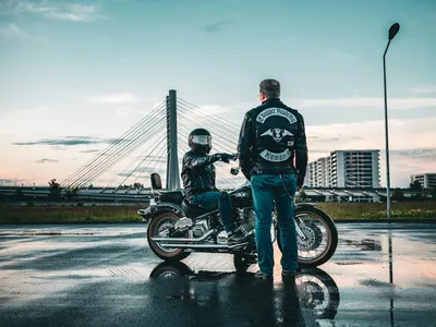 Two bikers meet near an urban bridge at sunset, creating a cinematic moment with 4k motorcycle wallpaper