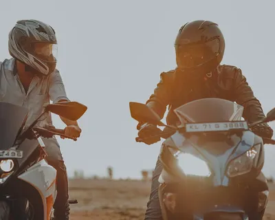 Two men riding motorcycles with helmets during sunset. Action and adventure conc 4k motorcycle wallpaper