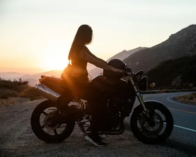 Woman on a motorcycle at sunset on a scenic mountain road. 4k motorcycle wallpaper