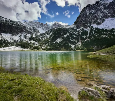 Captivating alpine lake view surrounded by snow-dusted mountain peaks under a vi 4k mountain wallpaper
