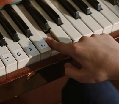 A person playing a labeled piano keyboard with finger pressing notes for learnin 4k music wallpaper