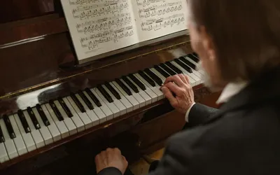 An elderly pianist plays a piano with sheet music, focusing on the keys in an in 4k music wallpaper