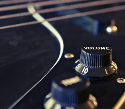 Detailed view of an electric guitar's volume knob with strings in the background 4k music wallpaper