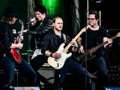 Rock band performing live with guitars and microphone on stage. Energetic and dy 4k music wallpaper