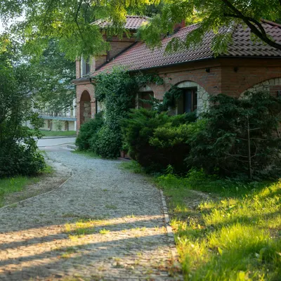 A picturesque view of a brick house surrounded by lush greenery and a stone path 4k nature wallpaper