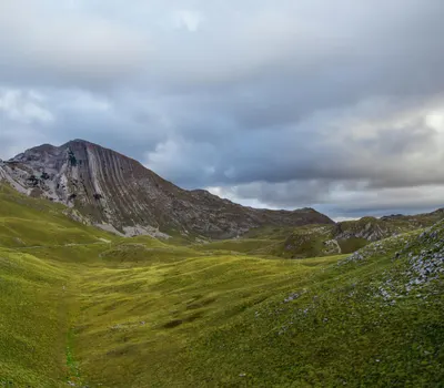 Beautiful view of a grassy mountain landscape under a cloudy sky in Montenegro. 4k nature wallpaper