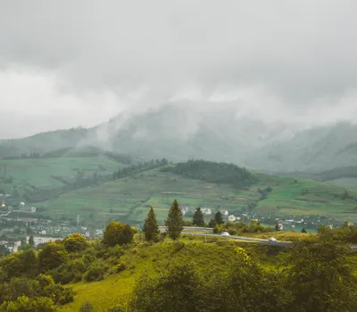 Serene view of a misty mountain landscape with a small village in the foreground 4k nature wallpaper