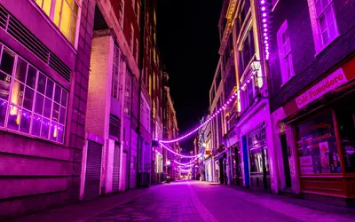 A city street illuminated by vibrant purple neon lights, creating a lively urban 4k neon wallpaper