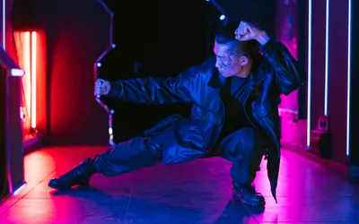 A man in a cyberpunk setting striking a dynamic pose with vibrant neon lighting. 4k neon wallpaper