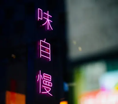 Bright pink neon Chinese characters glowing in a city night scene. 4k neon wallpaper