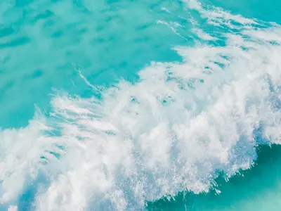 A stunning aerial shot of turquoise waves crashing in the vast ocean, creating a 4k ocean wallpaper