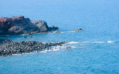 A scenic view of a rocky coastline meeting the clear blue ocean waters, ideal fo 4k sunset wallpaper